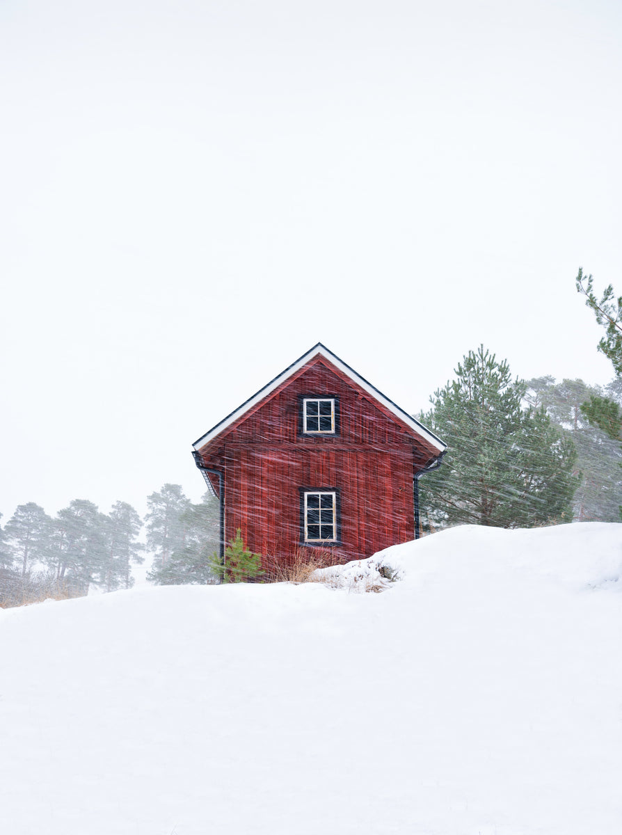 Gammelt rødt hus under snøstorm